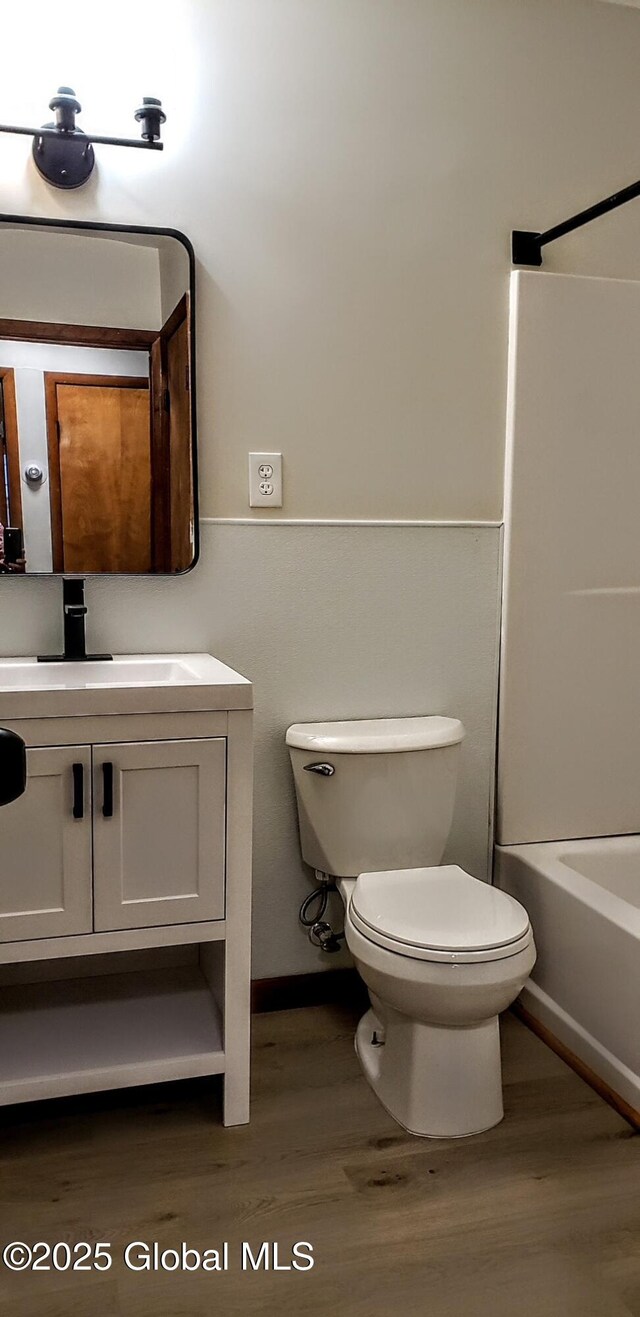 full bathroom with washtub / shower combination, toilet, wood finished floors, and vanity