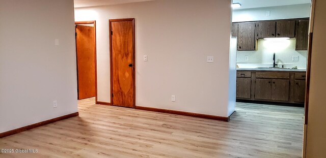 interior space with baseboards, light wood-style floors, and a sink