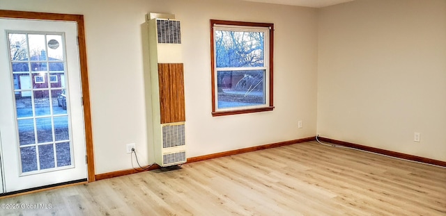 unfurnished room with a wealth of natural light, a heating unit, baseboards, and wood finished floors