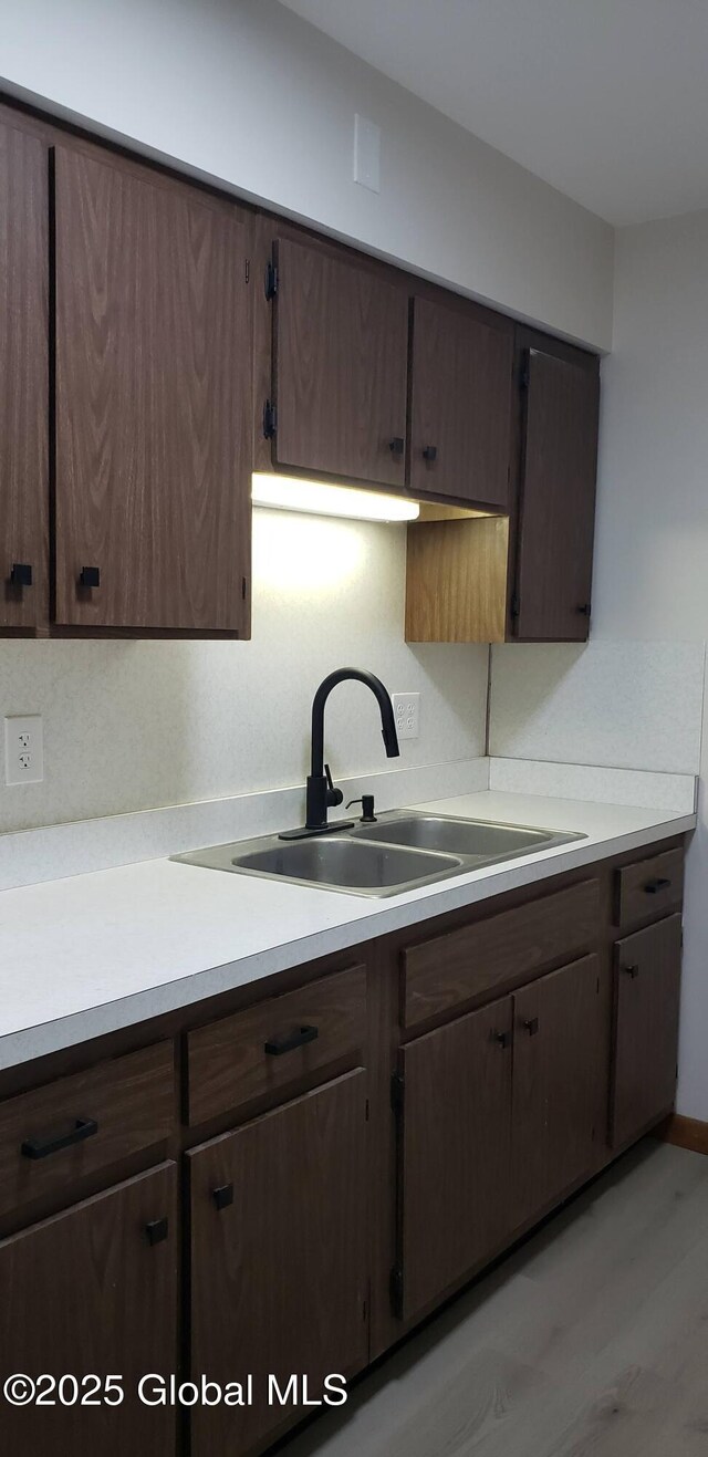 kitchen featuring a sink, dark brown cabinetry, and light countertops