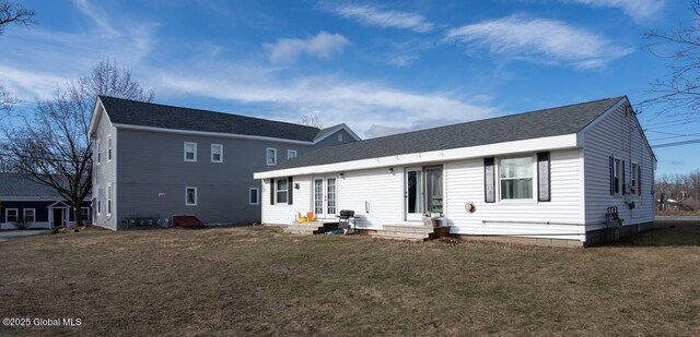 rear view of house featuring entry steps, a yard, and roof with shingles