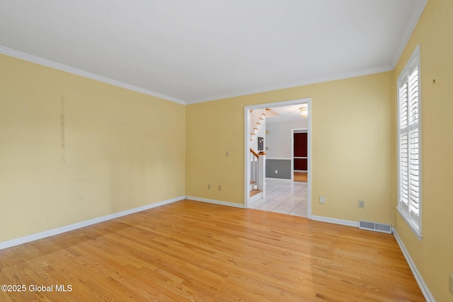 spare room featuring crown molding and light hardwood / wood-style floors