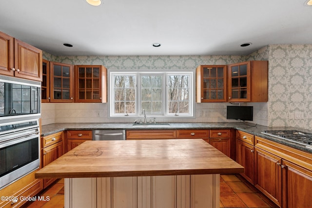 kitchen featuring wood counters, stainless steel appliances, a center island, light tile patterned flooring, and sink