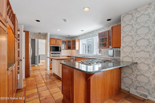 kitchen with tasteful backsplash, kitchen peninsula, a kitchen breakfast bar, and stainless steel appliances