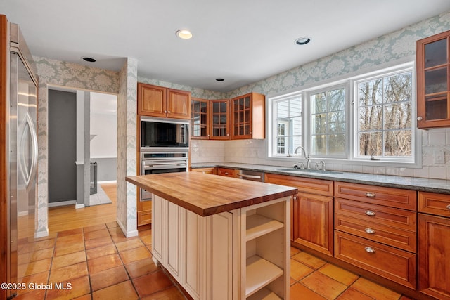 kitchen with appliances with stainless steel finishes, a kitchen island, butcher block counters, sink, and light tile patterned flooring