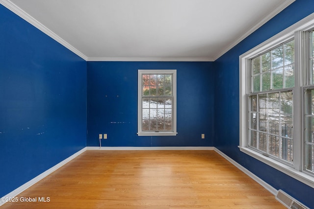 empty room featuring light wood-type flooring and crown molding