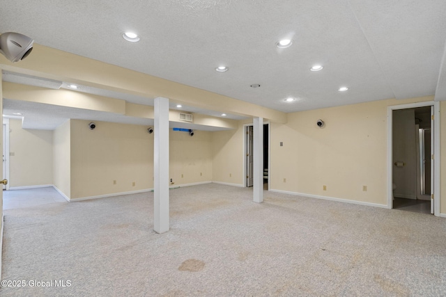 basement featuring light colored carpet and a textured ceiling