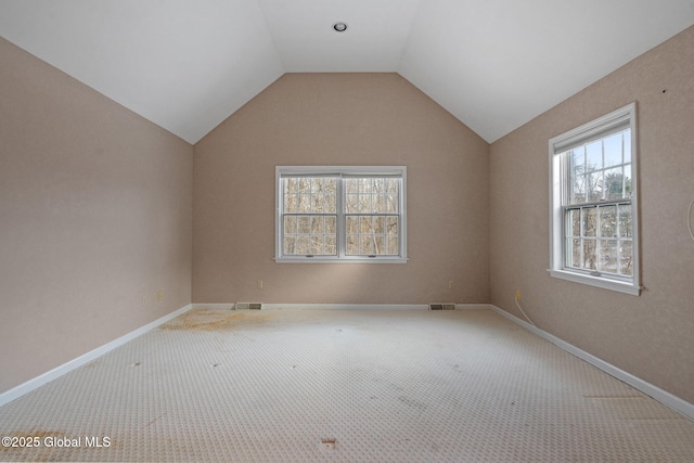 carpeted empty room featuring lofted ceiling