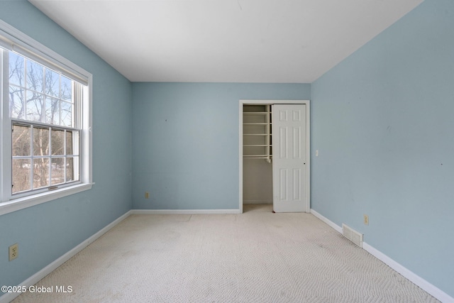 unfurnished bedroom with light colored carpet and a closet