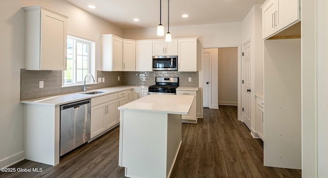 kitchen featuring white cabinets, decorative light fixtures, a kitchen island, and stainless steel appliances