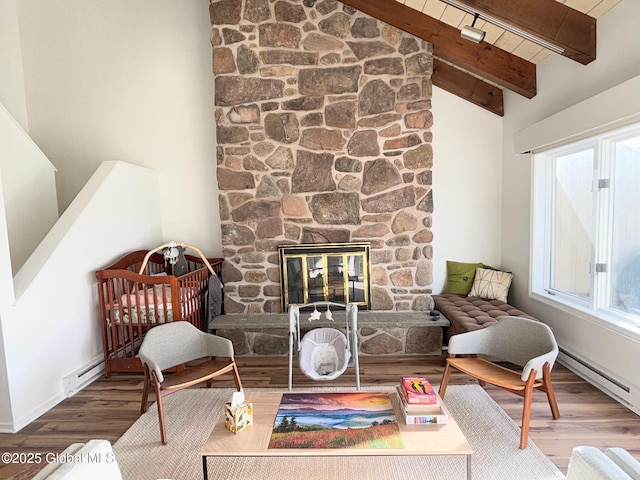 living area with hardwood / wood-style floors, lofted ceiling with beams, and a stone fireplace