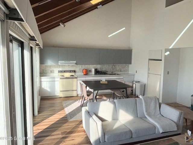 kitchen featuring white appliances, beamed ceiling, high vaulted ceiling, and tasteful backsplash