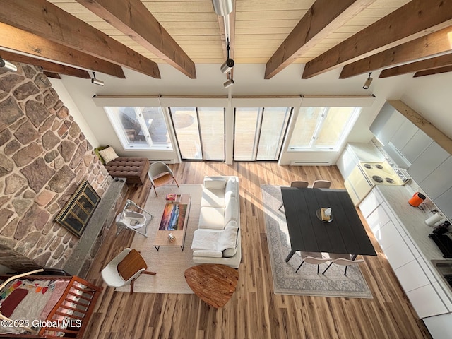 unfurnished living room with beam ceiling, a stone fireplace, wood ceiling, and hardwood / wood-style floors