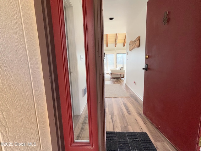 hallway with beam ceiling, light hardwood / wood-style flooring, and wooden ceiling