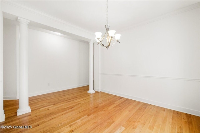 empty room featuring ornate columns, ornamental molding, hardwood / wood-style flooring, and an inviting chandelier