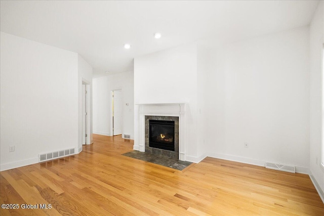 unfurnished living room with a tile fireplace and hardwood / wood-style floors