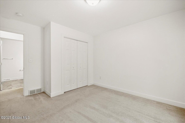 unfurnished bedroom featuring light carpet and a closet