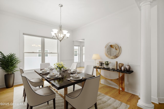 dining area featuring ornamental molding, light hardwood / wood-style flooring, a chandelier, and ornate columns