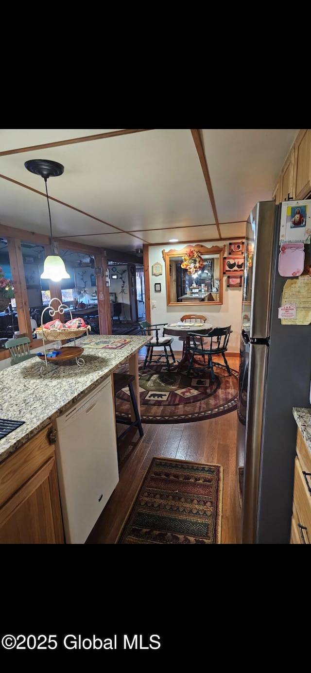 kitchen with light stone countertops, dark wood-type flooring, hanging light fixtures, stainless steel fridge, and white dishwasher