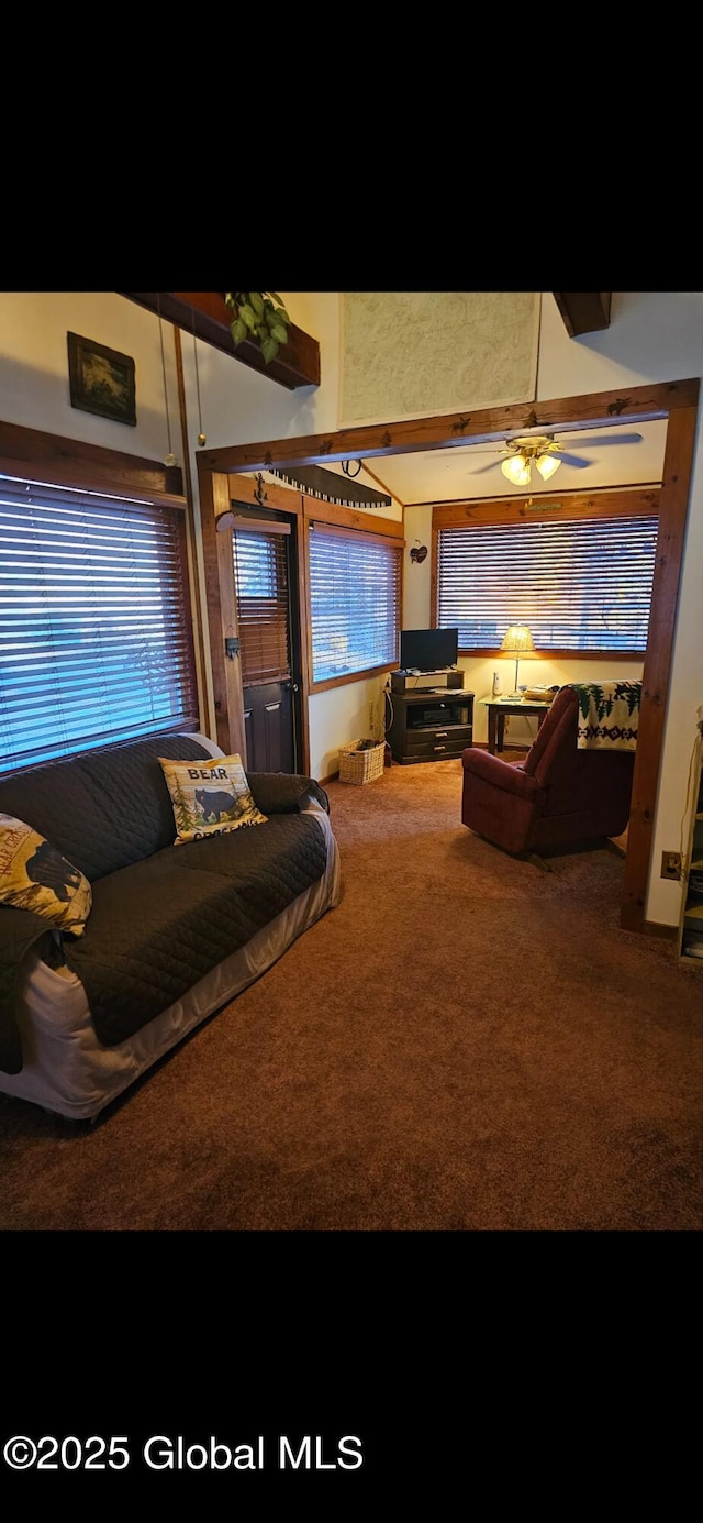 living room with ceiling fan, carpet flooring, and beamed ceiling