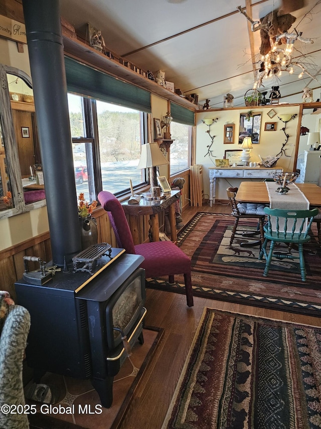 living room featuring dark wood-type flooring, a healthy amount of sunlight, a wood stove, and wood walls