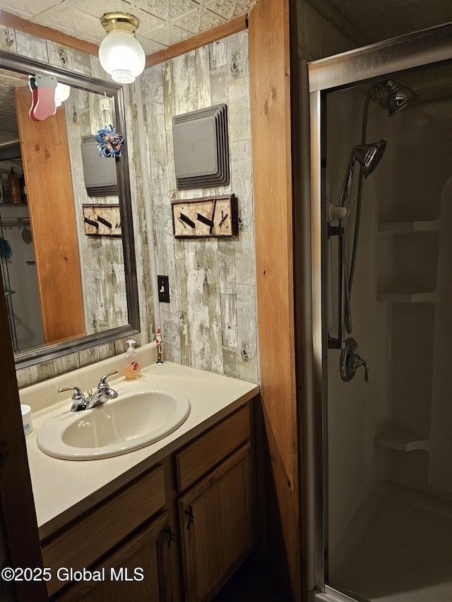 bathroom with an enclosed shower, vanity, and wooden walls