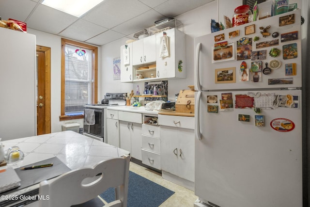 kitchen with a drop ceiling, white cabinets, and white appliances