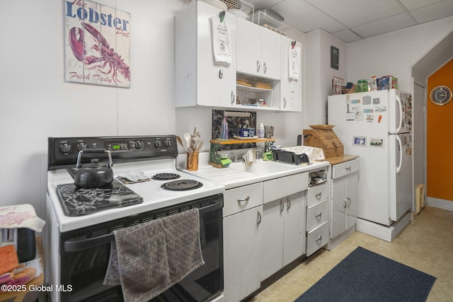 kitchen with white cabinets, a drop ceiling, range with electric stovetop, and white refrigerator