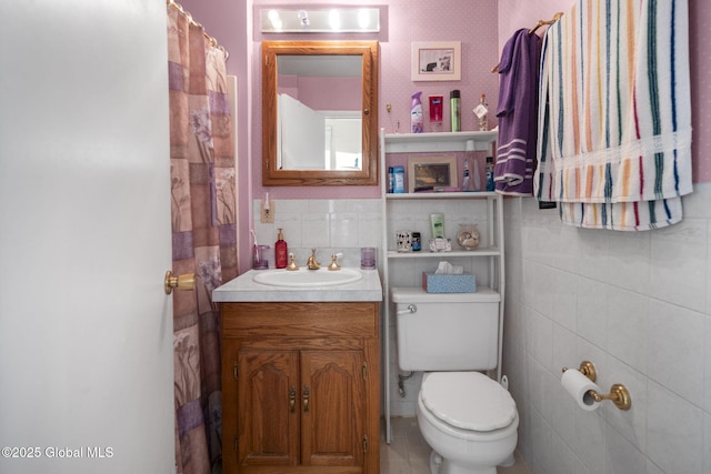 bathroom with vanity, tile walls, and toilet