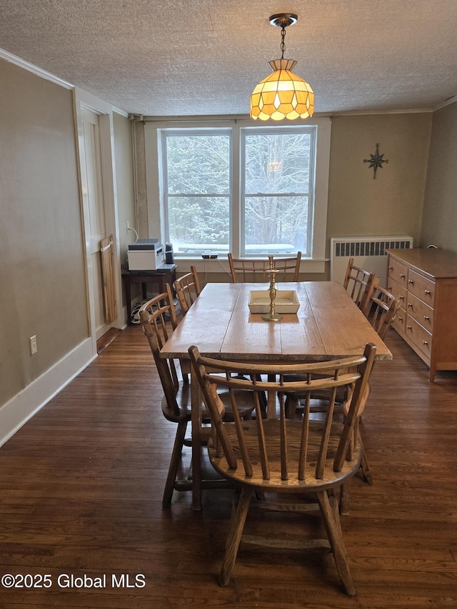 dining area with dark hardwood / wood-style flooring, radiator heating unit, a textured ceiling, and ornamental molding