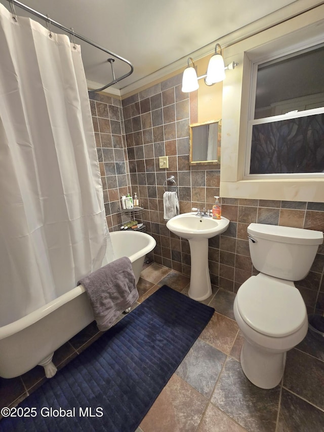 bathroom with toilet, tile walls, and shower / tub combo with curtain