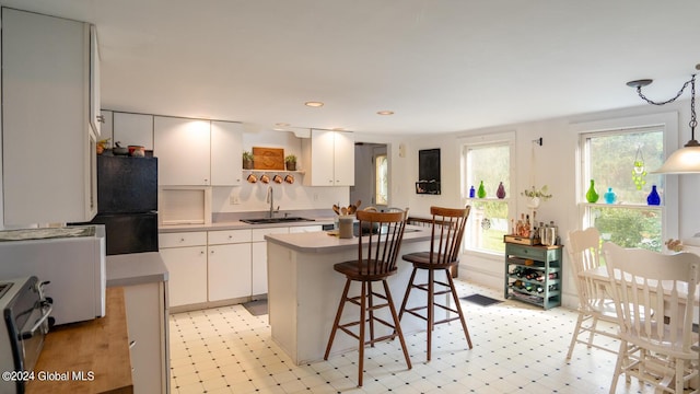 kitchen with white cabinetry, a kitchen island, sink, and hanging light fixtures