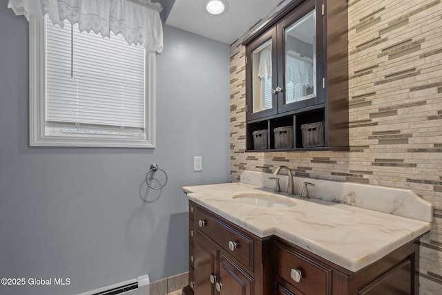 bathroom featuring vanity, backsplash, and a baseboard heating unit