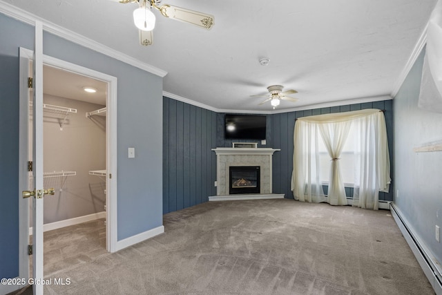 unfurnished living room featuring ceiling fan, crown molding, baseboard heating, and carpet flooring