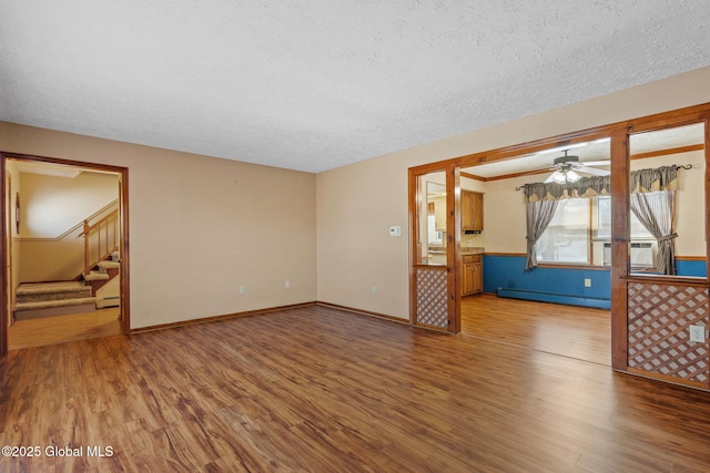 unfurnished room featuring wood-type flooring, ceiling fan, a textured ceiling, and baseboard heating