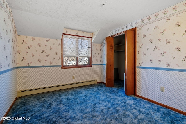 unfurnished bedroom featuring a baseboard radiator, dark carpet, a textured ceiling, and a closet