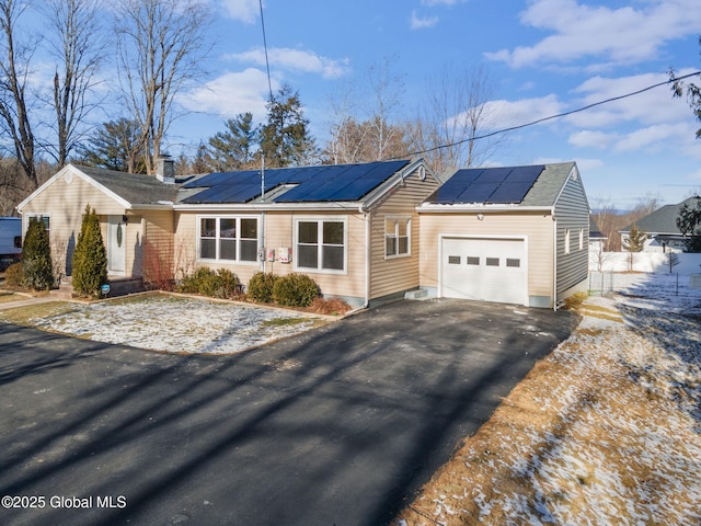 single story home with solar panels and a garage