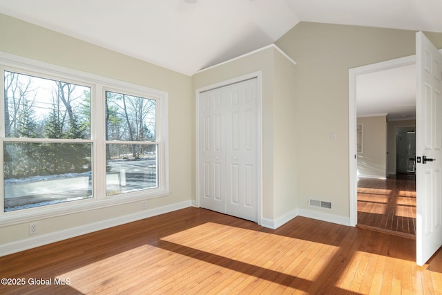 unfurnished bedroom featuring a closet, vaulted ceiling, and hardwood / wood-style flooring