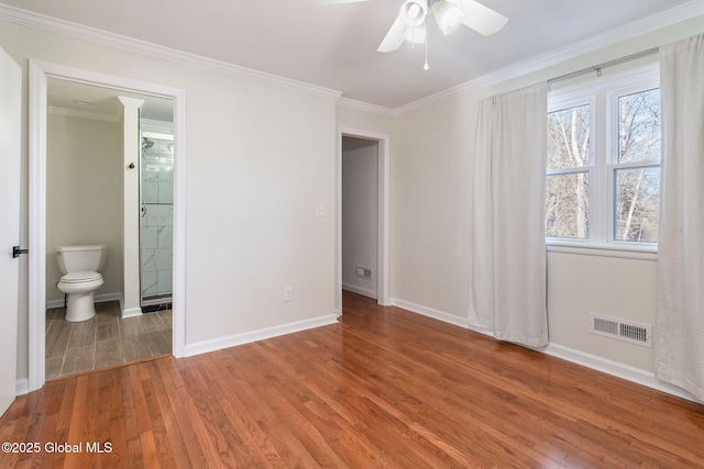 unfurnished bedroom featuring hardwood / wood-style flooring, ceiling fan, connected bathroom, and multiple windows