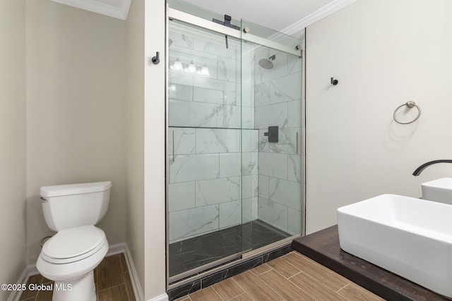 bathroom with toilet, an enclosed shower, ornamental molding, and sink