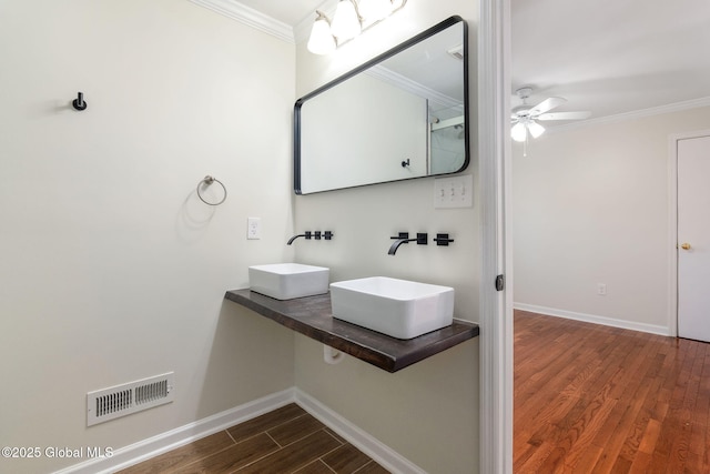 bathroom with ceiling fan, crown molding, dual sinks, and hardwood / wood-style flooring