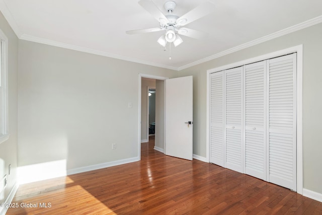 unfurnished bedroom with ceiling fan, a closet, wood-type flooring, and ornamental molding