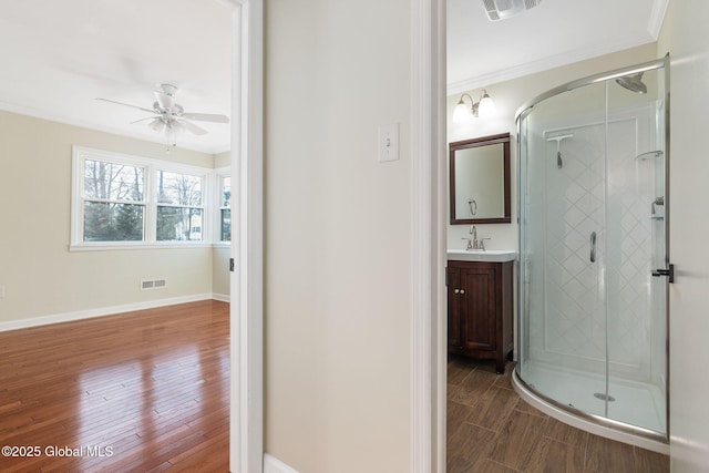 bathroom with vanity, a shower with door, ceiling fan, crown molding, and wood-type flooring