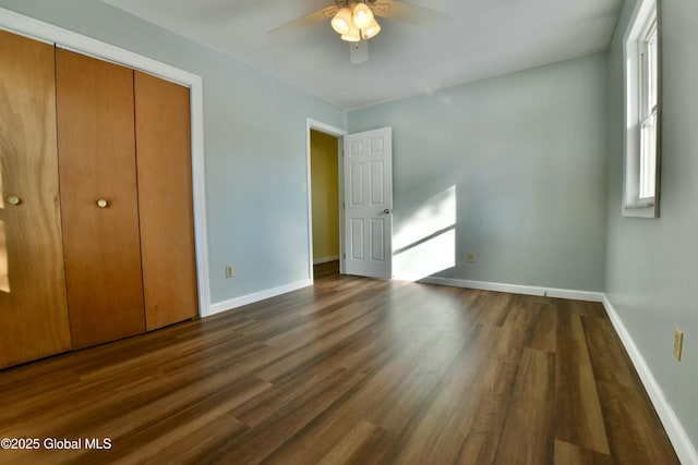 unfurnished bedroom featuring ceiling fan, multiple windows, dark hardwood / wood-style floors, and a closet