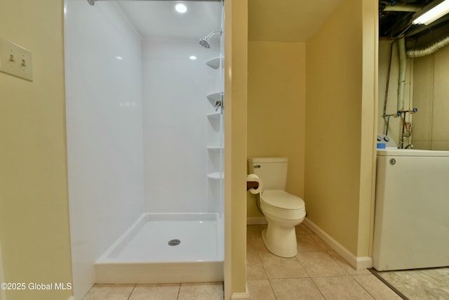 bathroom featuring a shower, tile patterned flooring, toilet, and washer / clothes dryer