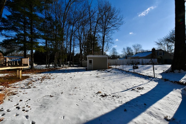 snowy yard featuring a storage unit