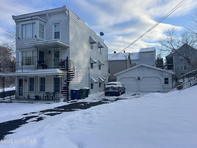 view of snow covered exterior featuring an outbuilding, a porch, and a garage