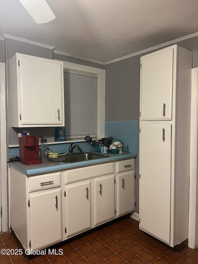 kitchen with white cabinetry, ornamental molding, and dark tile patterned floors