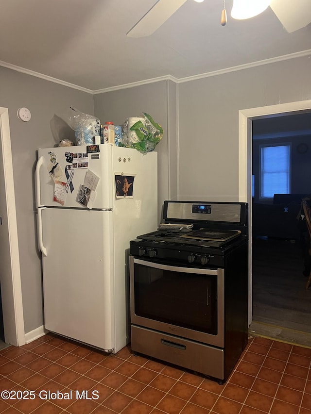 kitchen with white refrigerator, ornamental molding, dark tile patterned floors, and stainless steel gas range oven