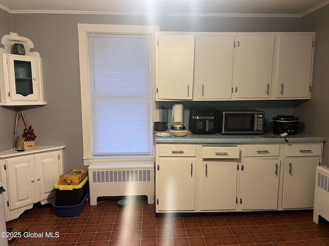 kitchen featuring crown molding, radiator heating unit, dark tile patterned floors, and white cabinets